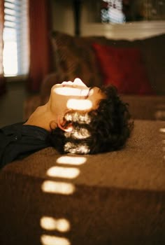 a woman laying on top of a couch next to a window