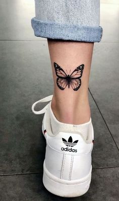 a woman's foot with a butterfly tattoo on the side of her shoe,