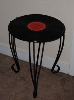 a small black table with an orange circle on it's top and metal legs