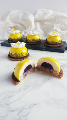 several desserts with yellow icing and white frosting are on a marble table