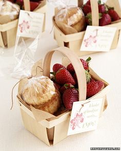 a basket filled with strawberries next to other small baskets full of bread and pastries