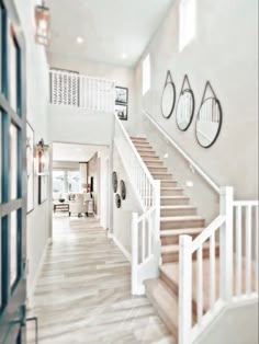 a large white staircase leading up to a living room with two clocks on the wall