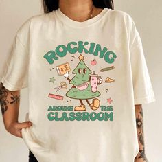 Roc'n Around The Classroom Christmas Tree Shirt! Whether you're a teacher, nurse, or school staff member, this fun and festive tee is perfect for spreading holiday cheer in the classroom or at work. Featuring a playful Christmas tree design and a humorous twist, it's a must-have for those who love celebrating the holiday season in style### HOW TO ORDER ### 1-) Check and Review all Photos. 2-) Select Your T-Shirt Size and T-Shirt Color from drop down menus. 3-) Select Your Design Print Color from Christmas Shirts Teacher, Classroom Christmas Tree, Teacher Christmas Shirts, Classroom Christmas, Teaching Shirts, Funny School, School Tees, Christmas Tree Shirt, School Staff