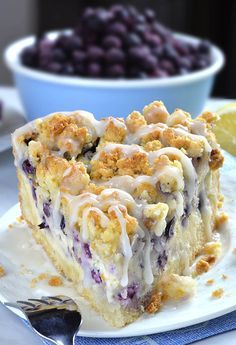 a slice of blueberry crumb cake on a white plate with a fork next to it