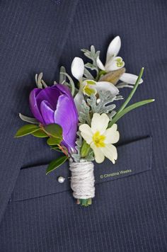 a boutonniere with purple and white flowers on the lapel of a suit