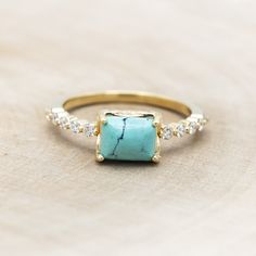 a gold ring with a turquoise stone and diamonds