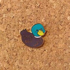 a pin with a duck on it sitting on a cork board background that says duck off