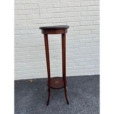 a small wooden table sitting in front of a white brick wall with a black top