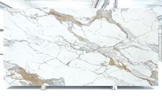 a white marble slab with gold veining on the top and bottom, sitting in a warehouse