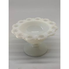 a white glass bowl with circles on the top and bottom, sitting on a pedestal