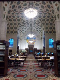 the inside of a library with many tables and bookshelves in it's center