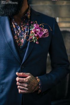 a man in a blue suit and flower boutonniere is holding his hands together