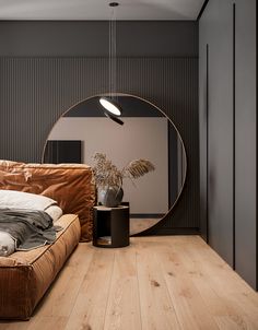 a living room with a round mirror on the wall next to a couch and potted plant