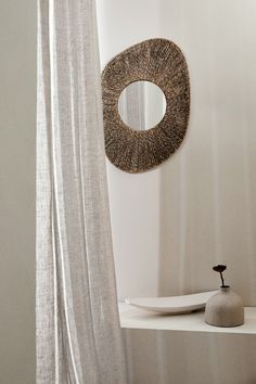 a white bathroom with a round mirror on the wall next to a bathtub and shower curtain