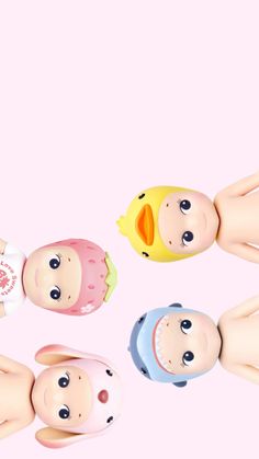 five dolls with different colored faces are in a circle on a pink background and one is holding a cell phone