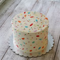 a white cake with sprinkles on it sitting on top of a doily