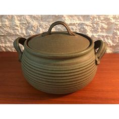 a green pot sitting on top of a wooden table