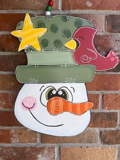 a painted snowman hanging on a brick wall