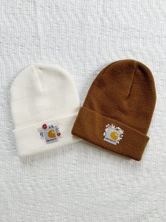 two beanies sitting next to each other on top of a white sheet covered surface