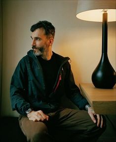 a man sitting in front of a lamp on a table next to a wooden desk