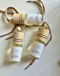 two bottles of perfume sitting next to each other on a white surface with twine