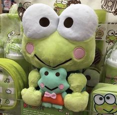 a green stuffed animal sitting on top of a pile of diapers in a store