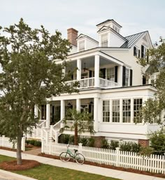 a white house with black shutters and a bicycle parked in front of the house