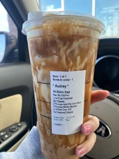 a woman holding up a cup of iced coffee in her hand with the label on it