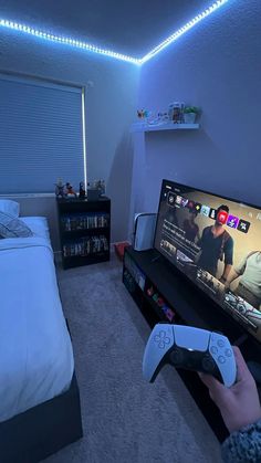 a person holding a nintendo wii game controller in front of a tv with the lights on