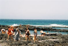 many people are walking on the rocks near the water