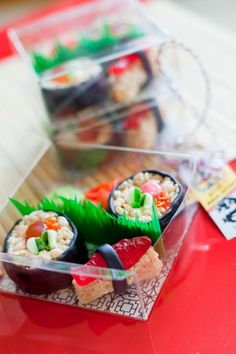 some sushi is in a plastic container on a red table