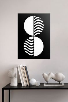 a black and white abstract art piece on a wall above a table with two books