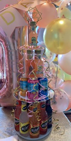 there is a cake made to look like a tower with beer bottles on it and balloons in the background