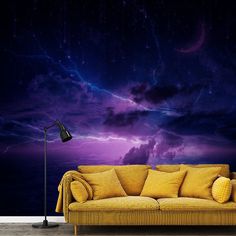 a yellow couch sitting in front of a wall with a purple sky and stars on it