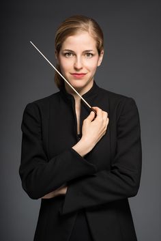 a woman in black jacket holding a violin on top of her shoulder and looking at the camera