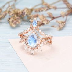 an image of a ring with diamonds and blue stones on the front, sitting on top of a piece of paper