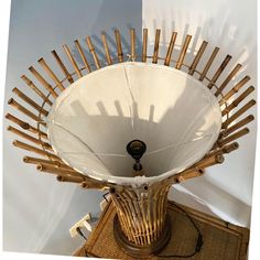 a wooden table topped with a white lamp shade