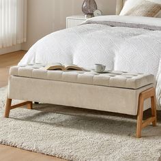 a bed with a book on it and a coffee cup sitting on the foot board