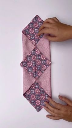 someone is holding up a pink tie on a white surface