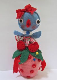 a stuffed animal sitting on top of a strawberry with red bows and green leaves in its mouth