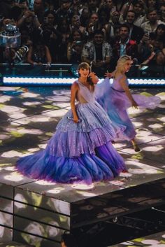 two women in purple dresses are dancing on stage