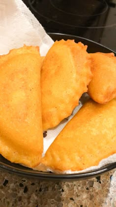 three fried food items in a black bowl on a counter next to a white paper towel