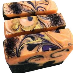 three bars of soap with black and gold designs on them, one bar is yellow