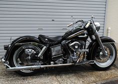 a black motorcycle parked in front of a garage door