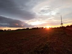 the sun is setting over an empty field