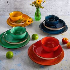 a table topped with lots of colorful plates and bowls filled with fruit next to each other