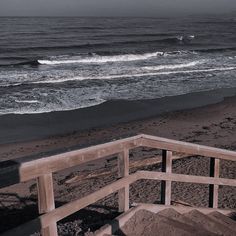 the stairs lead down to the beach where waves are coming in and there is no one on it