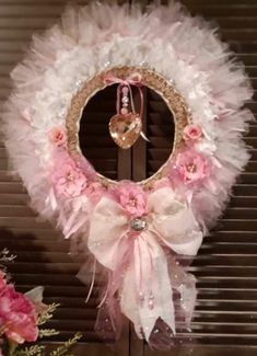 a pink and white wreath hanging from the side of a door with flowers on it