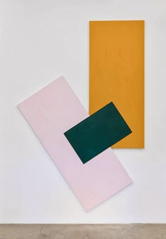 three different colored papers on a white surface with one green and the other yellow in color