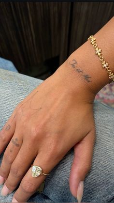 a person with a tattoo on their arm wearing a gold bracelet and a diamond ring